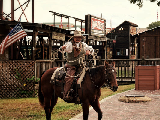 Cowboy on horseback holding a lasso in a western town