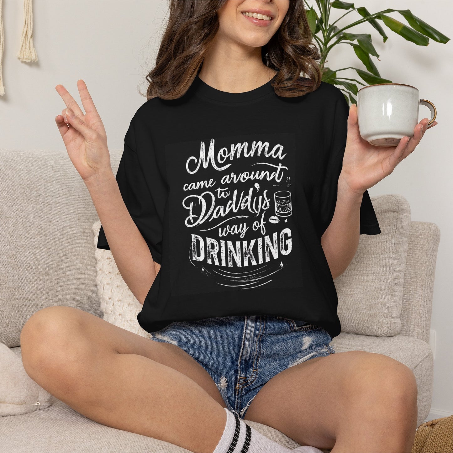 Unisex Drinking T-shirt in black featuring playful text design. Model poses with a cup, styled casually.