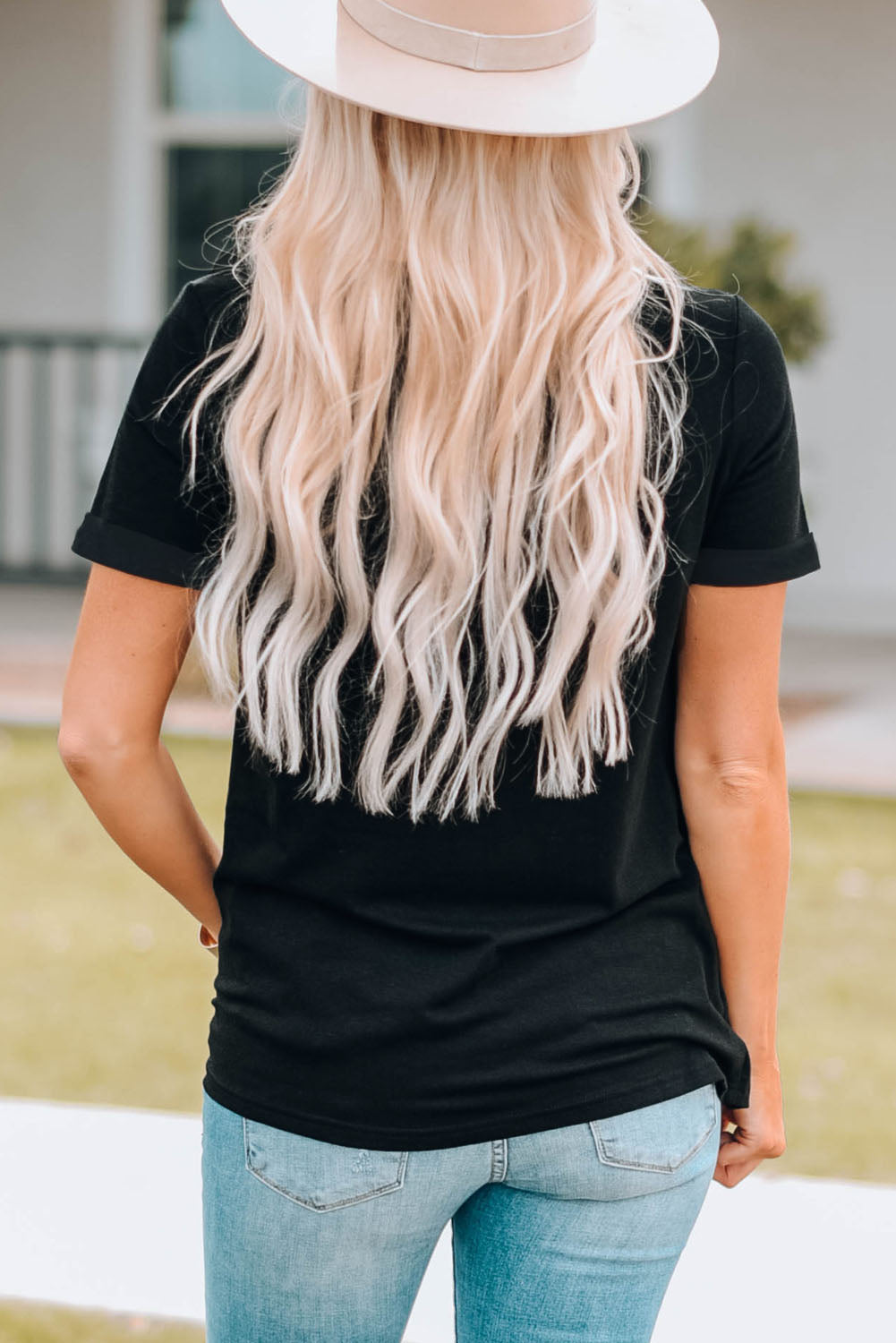 Black Graphic Cuffed Sleeve Round Neck Tee worn by a woman with long blonde hair, paired with light blue jeans.