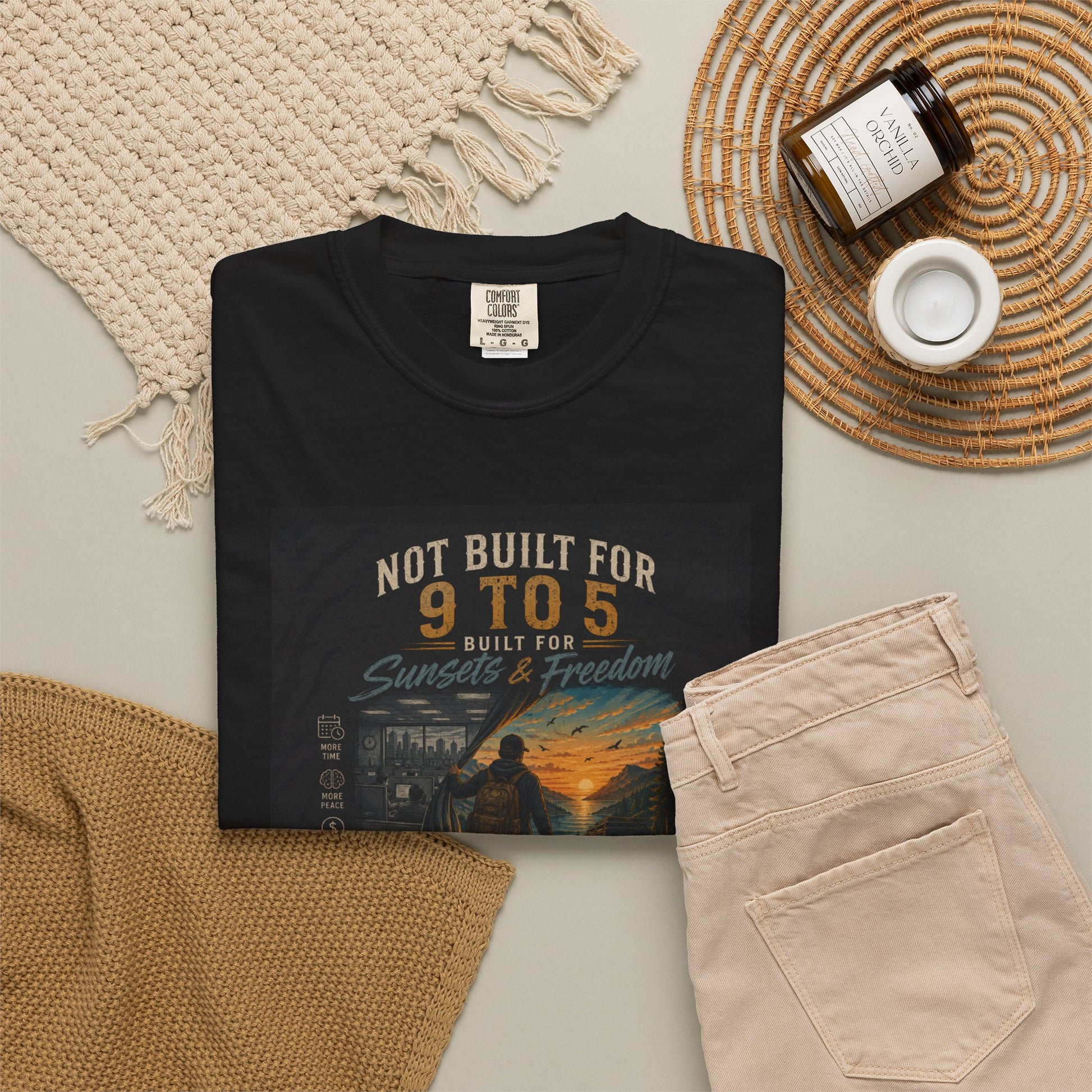 Black "Not Built for 9 to 5" T-Shirt displayed with beige pants, a woven placemat, and a candle, emphasizing a casual style.