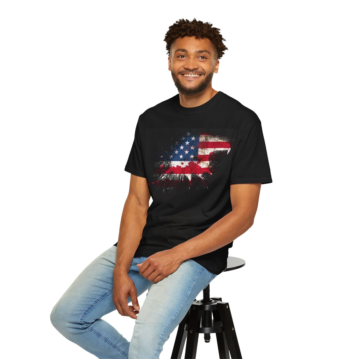 Unisex Garment-Dyed T-shirt featuring a distressed American flag design, modeled by a smiling man on a stool.