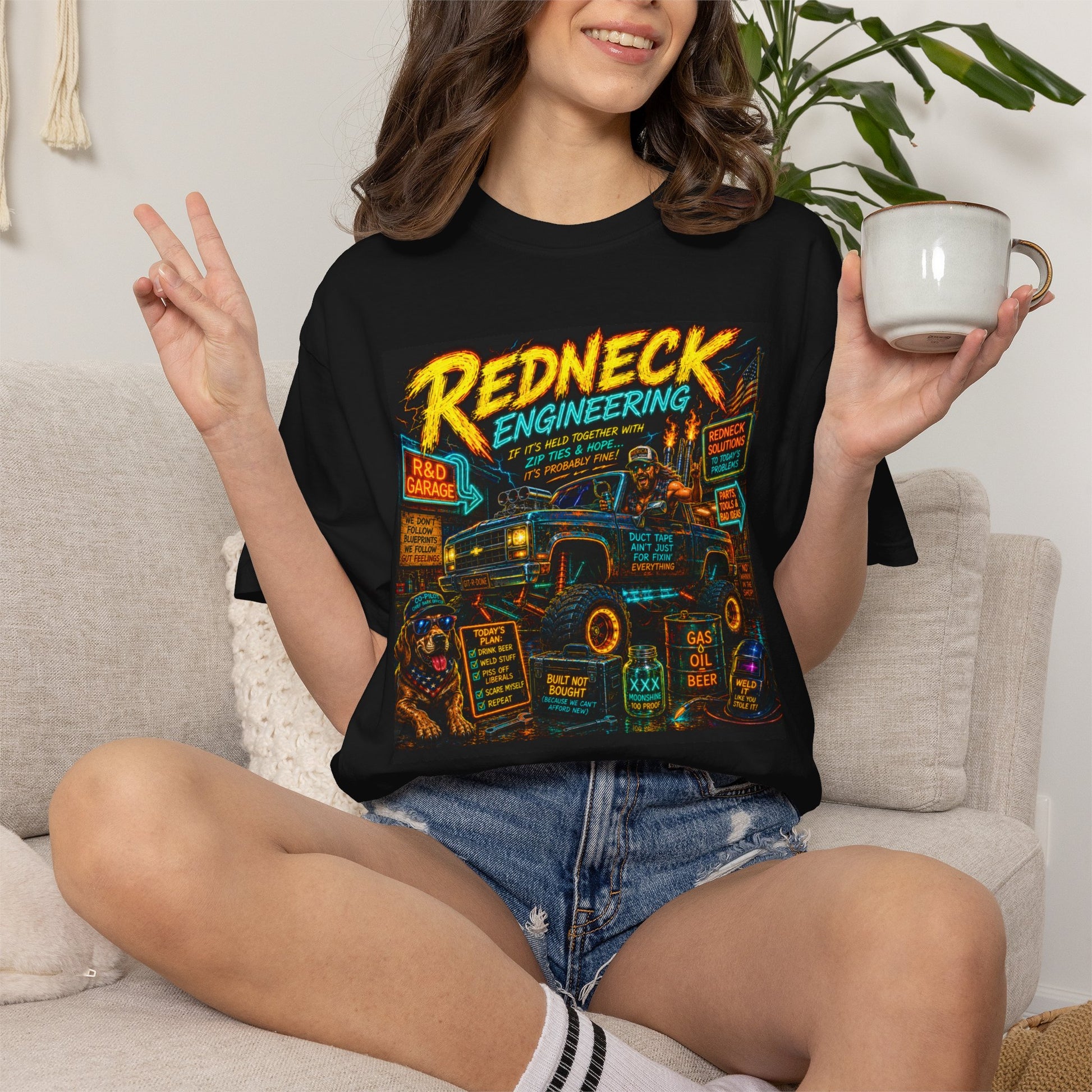 Vintage Garment-Dyed T-Shirt #14 features a colorful "Redneck Engineering" graphic on a black shirt, worn by a woman holding 